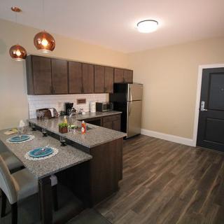 A modern kitchen with a dining area featuring sleek cabinets, a countertop, and stylish lighting.