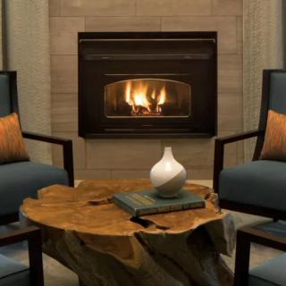 A cozy living room with a fireplace, two armchairs, and a rustic wooden table.