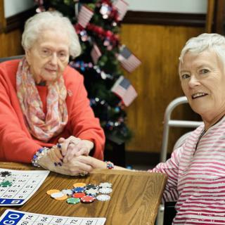 Two elderly women enjoying a game of bingo indoors.