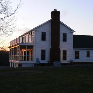 A two-story house with a chimney, basking in the glow of a sunset.