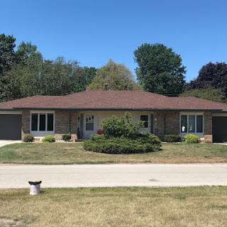 A charming single-story house with a well-maintained lawn under a clear blue sky.