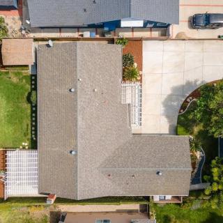 Aerial view of a suburban house with a spacious driveway and backyard.