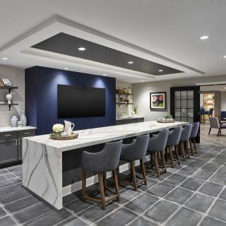 A modern kitchen and bar area with a large island counter and stylish seating.