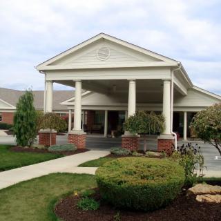 A view of a building entrance featuring columns and landscaped surroundings.