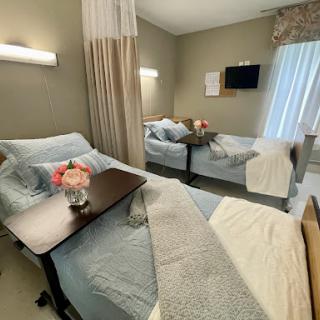 A well-appointed hospital patient room featuring two beds, soft lighting, and decorative touches for a comfortable stay.
