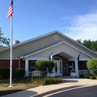 A building with an American flag in front, surrounded by trees under a clear blue sky.