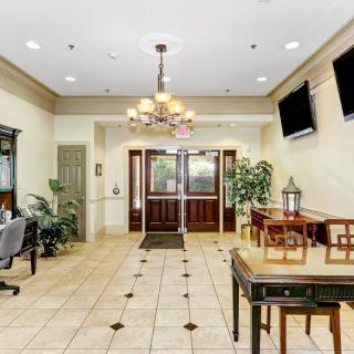 A well-lit lobby area featuring seating, a chandelier, and decorative plants.