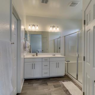 A modern bathroom with a double sink, large mirror, and a glass-enclosed shower.