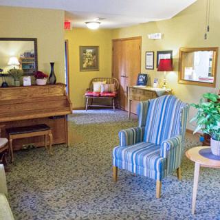 A cozy living room featuring a piano, striped armchair, and various home decor elements.