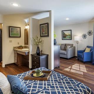 A cozy and modern interior space combining a living area and bedroom with stylish furniture and wood flooring.