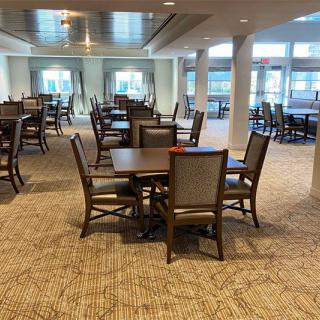 A spacious dining area featuring several tables and chairs, illuminated by natural light.