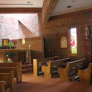 The serene interior of a brick church, featuring wooden pews and an altar bathed in natural light.