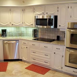 A modern kitchen with white cabinetry and stainless steel appliances.