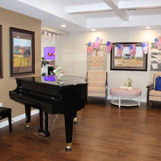 A cozy lounge area featuring a black piano, elegant seating, and decorative artwork.