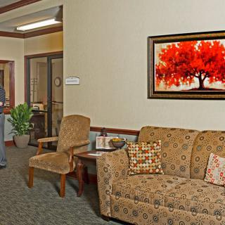 A cozy waiting room with a sofa, chairs, and a vibrant painting on the wall.