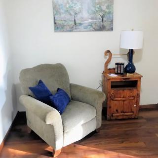 A cozy corner with an armchair, side table, and lamp in a warmly lit living room.