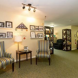 A cozy living room with striped chairs, wall decorations, and ambient lighting.