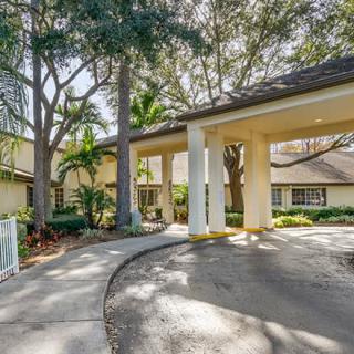 A residential building with a covered entrance and surrounding trees.