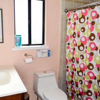 A bathroom featuring a toilet, sink, and a colorful shower curtain with circular patterns.