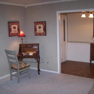 Cozy living room corner with a small wooden desk, chair, and decorative wall art.