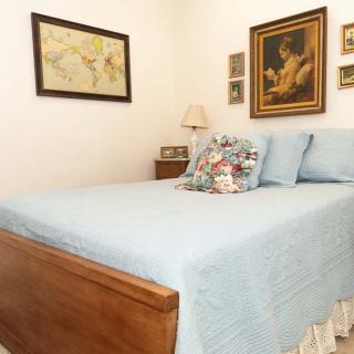 A cozy bedroom with blue bedding and various artworks on the walls.
