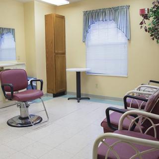 An empty hair salon with chairs and a mirror, featuring a small waiting area.