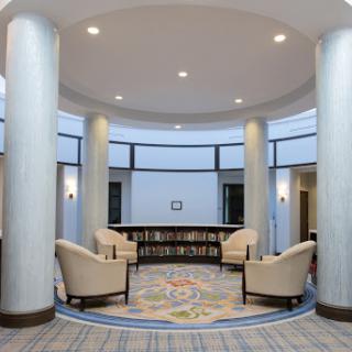 A modern lobby featuring comfortable seating, decorative columns, and a bookshelf.