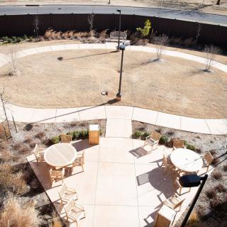 An aerial view of a courtyard featuring outdoor seating with tables and chairs arranged on a paved patio area.