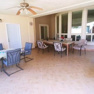 A spacious patio with multiple seating arrangements, including tables and chairs, under a ceiling fan.