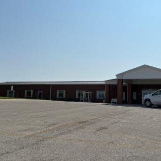 A view of a commercial building with a parking lot under a clear blue sky.
