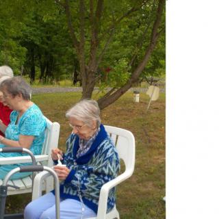 A group of elderly women sitting on chairs outdoors in a park.