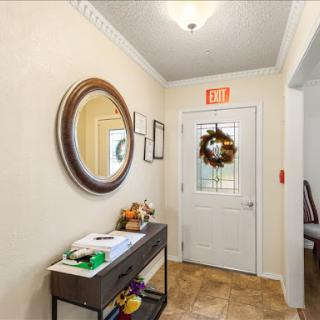 A welcoming entrance featuring a mirror, a decorative wreath on the door, and a console table with various items.