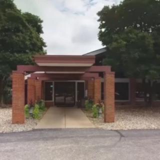 A brick building entrance with a covered pathway surrounded by trees.