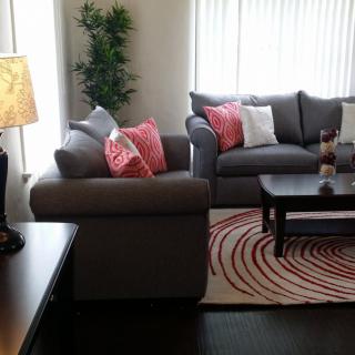 A cozy living room with grey sofas, colorful cushions, and a patterned rug.
