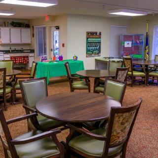 A community dining area with wooden tables and chairs, set in a welcoming indoor environment.