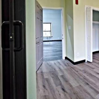 An interior view of an empty room with wood flooring, featuring a closet and a window.