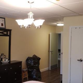 A bedroom interior featuring a chandelier, dresser with mirror, and an open doorway.