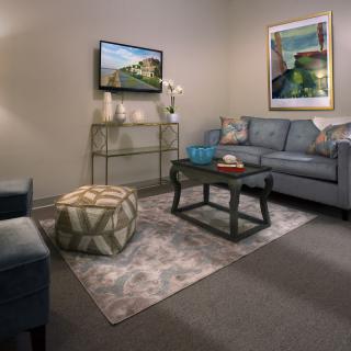 A cozy living room with a sofa, coffee table, rug, and wall-mounted television.