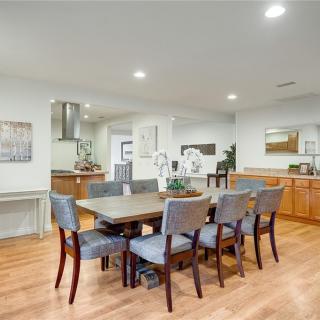 A modern dining room with a wooden floor and stylish dcor, featuring a spacious dining table set within an open-concept living area.