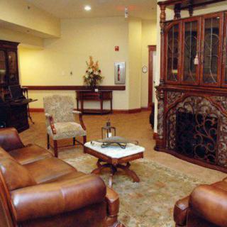 A cozy living room with leather seating, a coffee table, and an ornate fireplace.