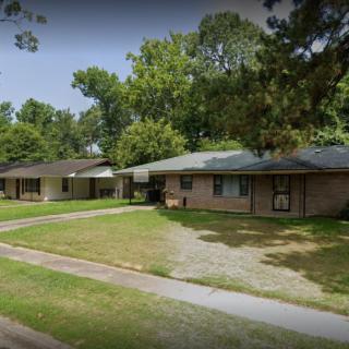 A suburban neighborhood with single-story houses and a well-maintained lawn.
