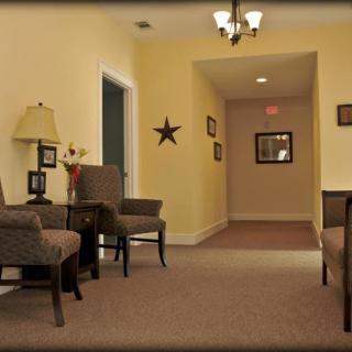 A cozy waiting room with chairs and decor along a carpeted hallway.