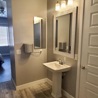 A modern, minimalist bathroom with a pedestal sink and large mirrors.