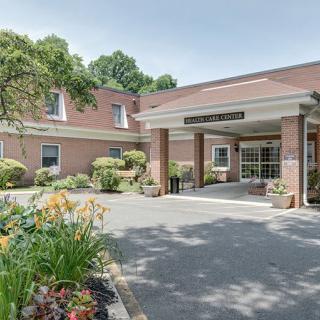 The front entrance of a brick building with landscaped gardens and flowers.
