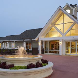 A well-lit building with a fountain in front during the evening.