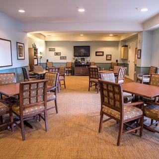 A cozy dining area with multiple tables and chairs, adorned with framed pictures and a television on the wall.