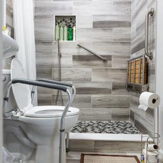 A stylish and modern bathroom featuring a combination of textured tiles, an accessible shower area, and thoughtful storage solutions.