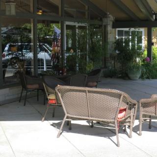 An outdoor patio area with wicker seating and glass windows reflecting the surroundings.