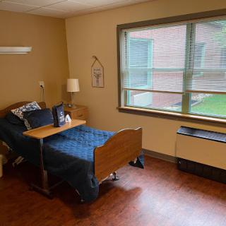 A cozy room with a single bed, lamp, and window view.