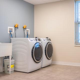 A clean and modern laundry room featuring a washing machine, dryer, and utility sink.